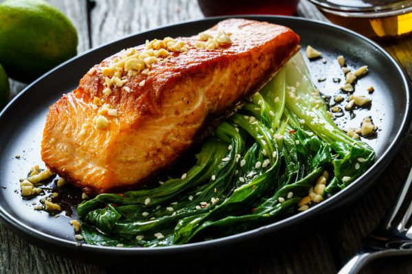 Fish dish - salmon steak with pak choi cabbage on wooden table