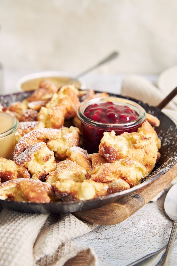 Vertical shot of kaiserschmarrn with torn pancakes, cranberries jam, and apple puree on a table