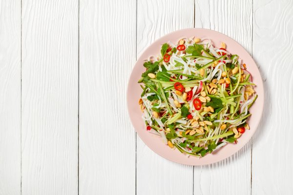 Rice noodle and vegetable salad on a plate on a wooden table, asian cuisine, horizontal view from above, flat lay, free space